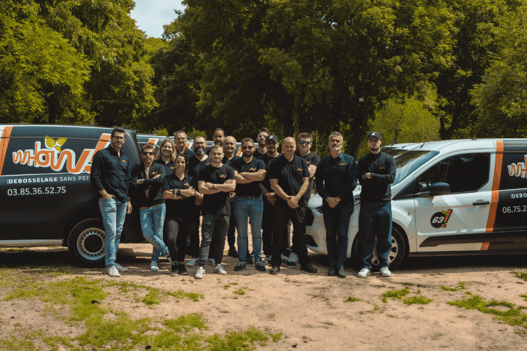 Groupe de techniciens devant deux véhicules en plein air, entourés d'arbres.