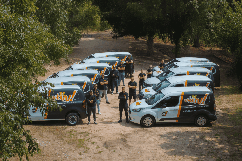 Équipe de techniciens de dépollution face à des véhicules de service dans un parc ombragé.
