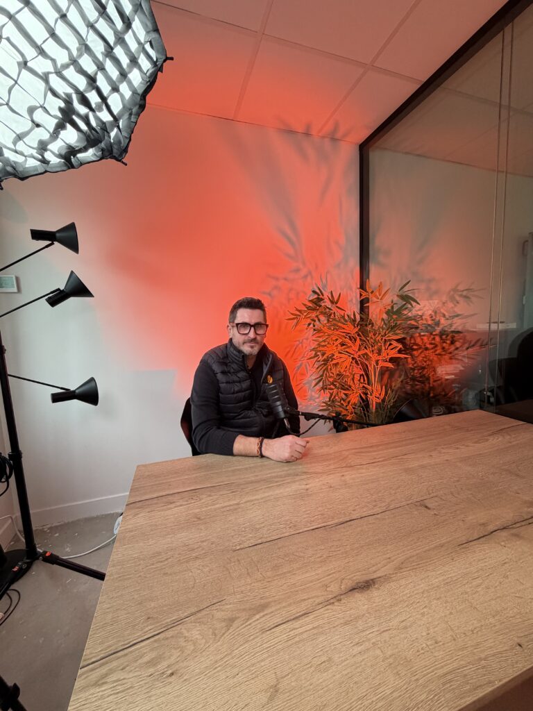 Homme assis à une table en studio avec éclairage rouge et plantes